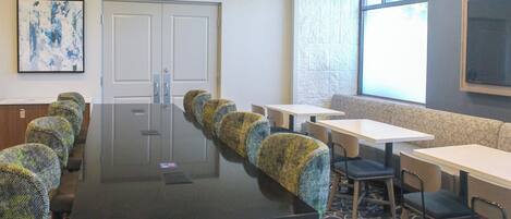 Un salón de conferencias con una larga mesa, sillas y un amplio ventanal.