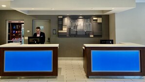 A hotel reception area with two reception desks, a wall-mounted sign, and a counter with snacks.