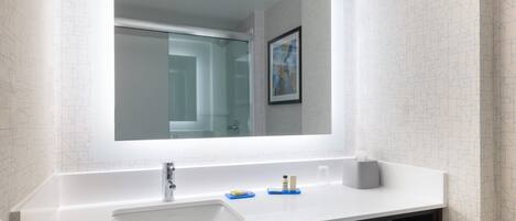A modern bathroom with a large mirror, white sink, and a towel rack.