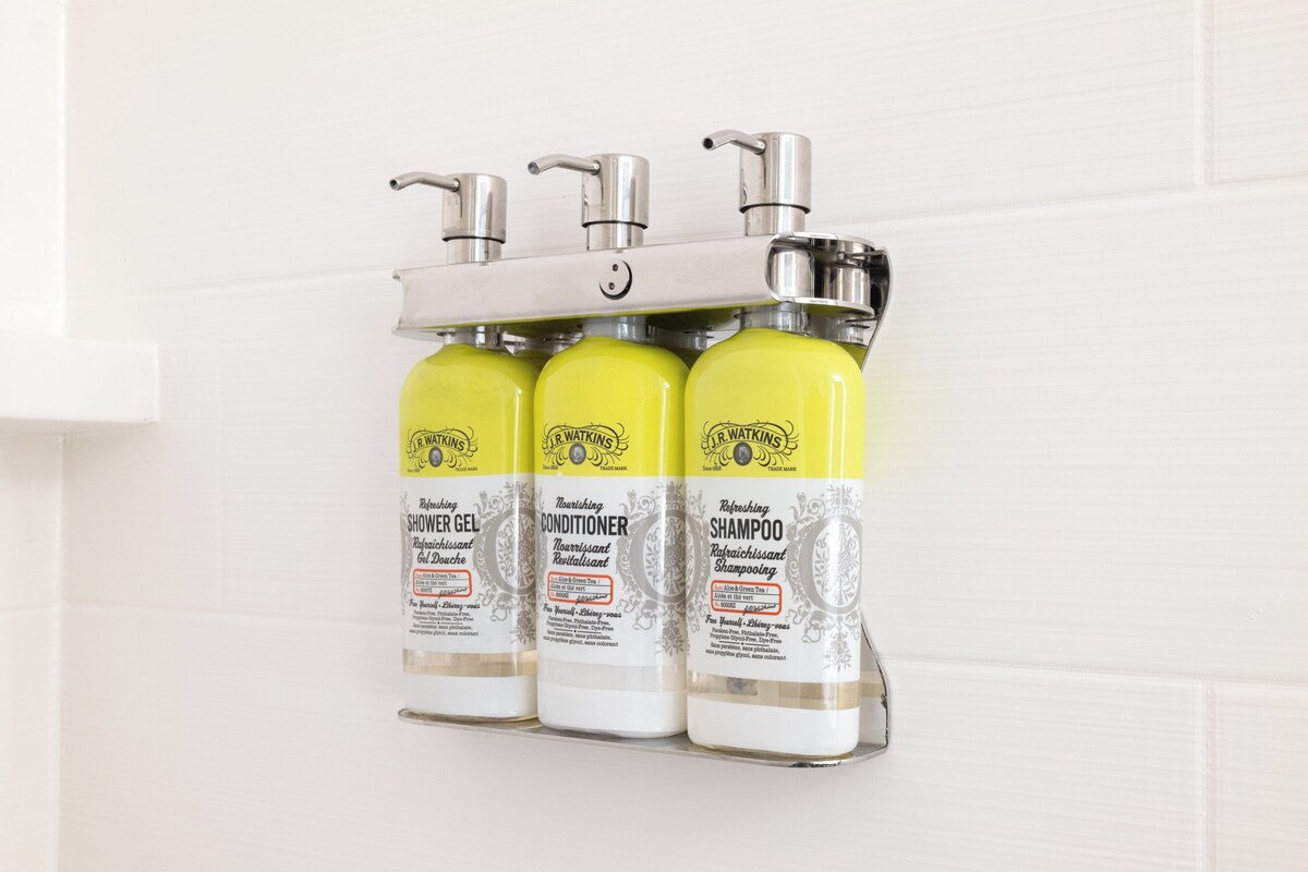 Three bottles of R. Watkins hair care products mounted on a wall.