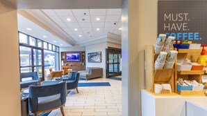 A modern coffee shop with seating, a television, and a coffee display.