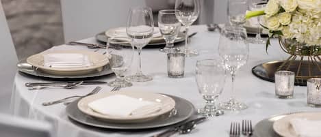 A table set for a formal dinner with white plates, silverware, and clear glassware.