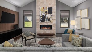 Una sala de estar moderna con chimenea de piedra, un televisor de pantalla plana y asientos cómodos.