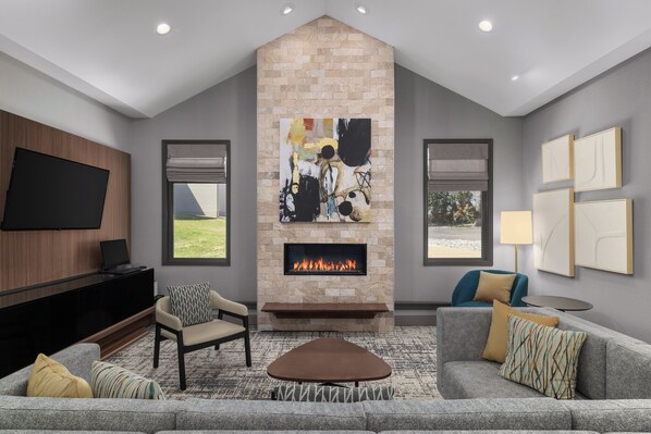 Una sala de estar moderna con chimenea de piedra, un televisor de pantalla plana y asientos cómodos.