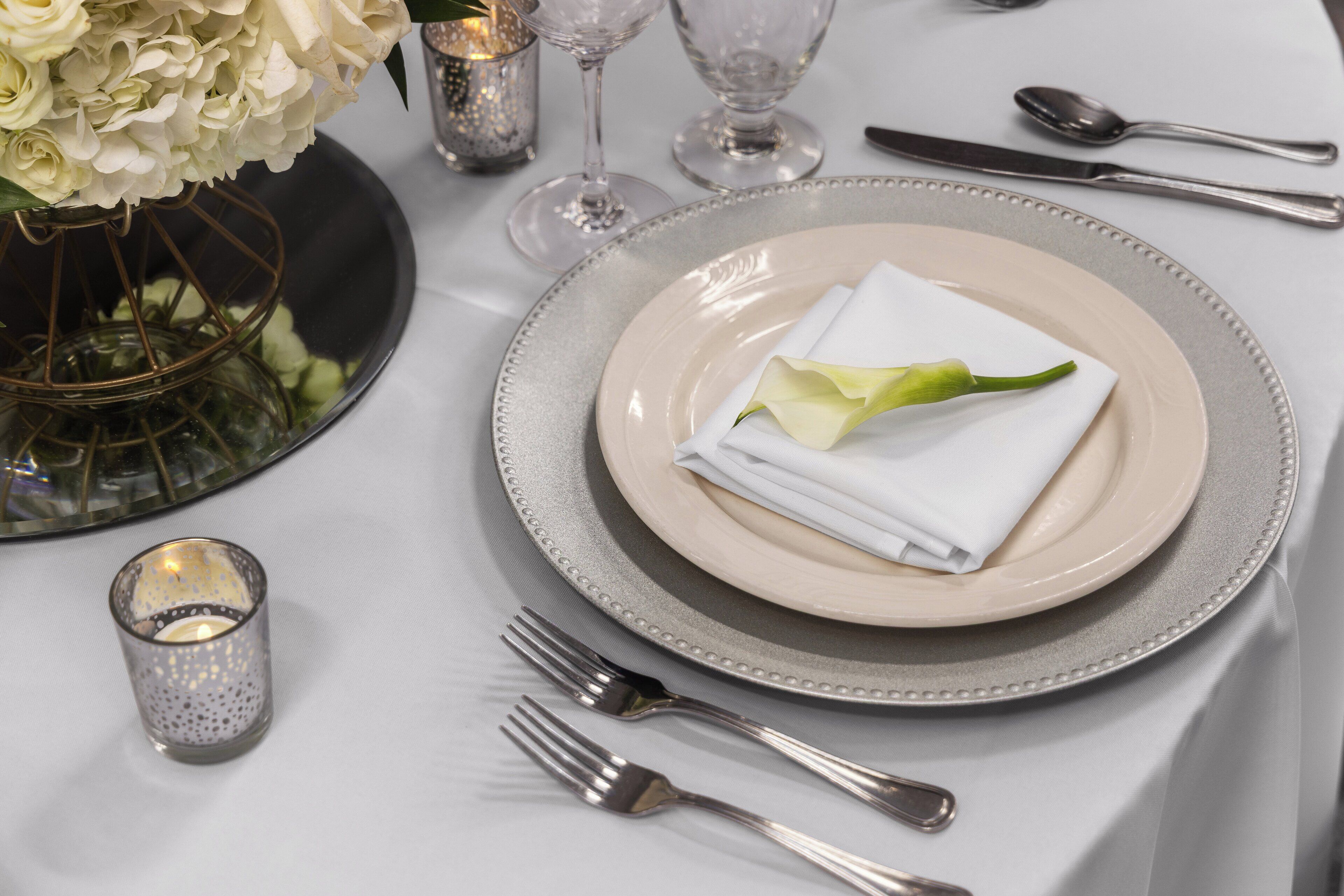 A table set with a plate, folded napkin, and a green leaf.