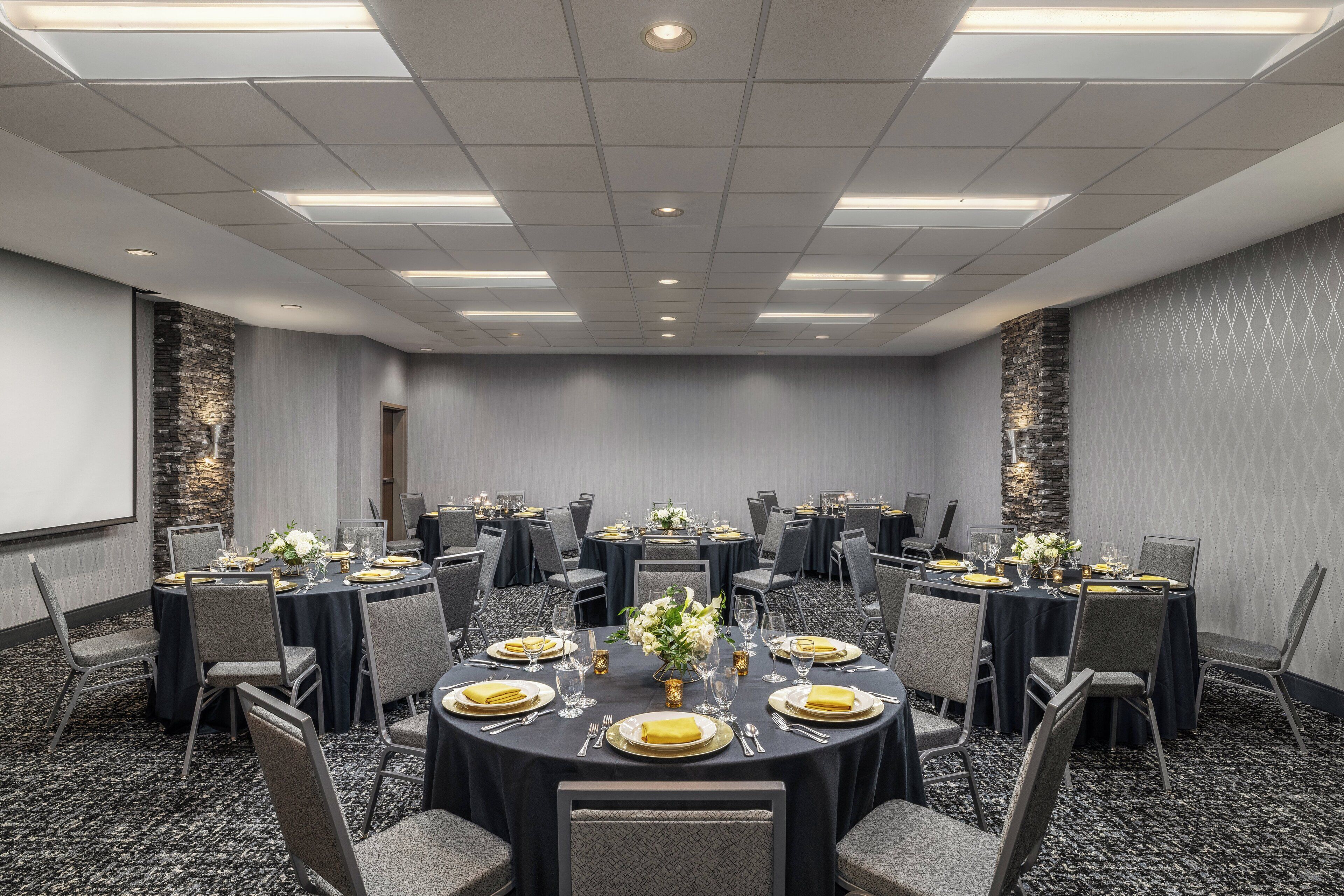 A conference room with round tables, chairs, and a projector screen.