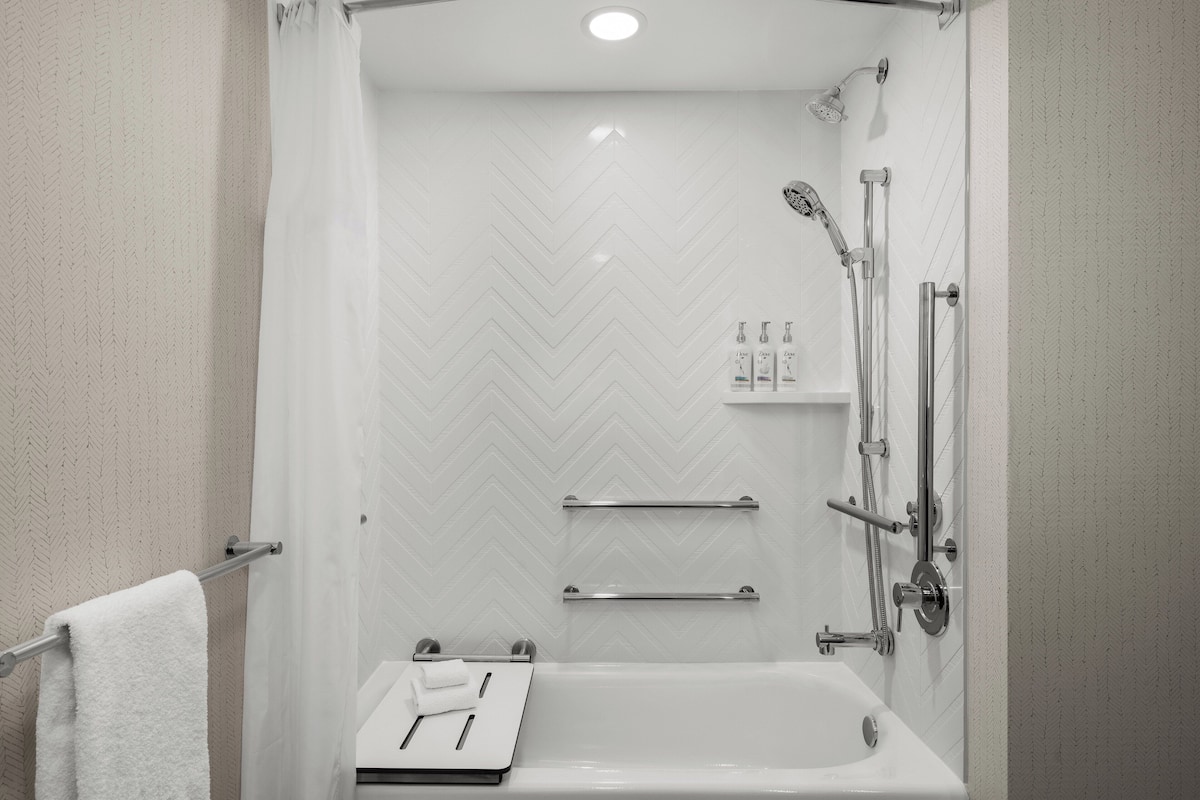 A modern bathroom with a shower, a bathtub, and a towel rack.