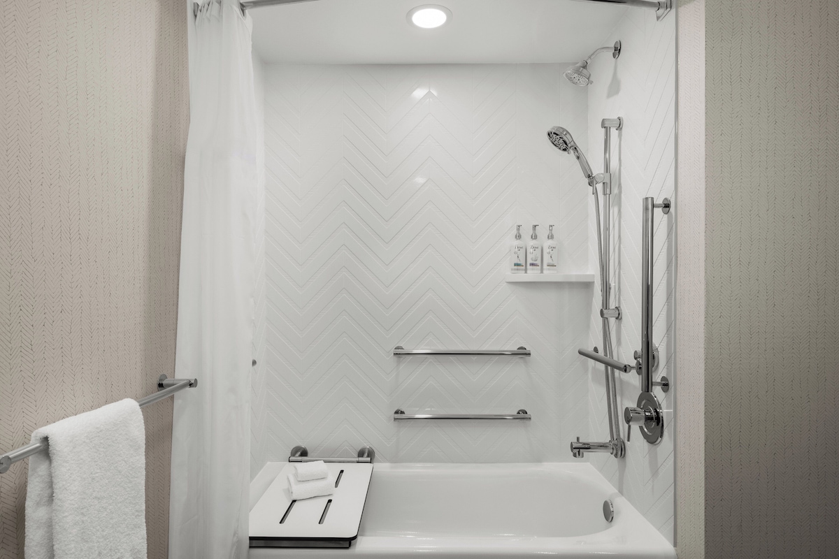 Un baño moderno con ducha, bañera y toallero.