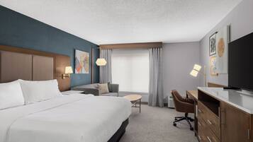 A hotel room with a large bed, a desk, a chair, and a TV.