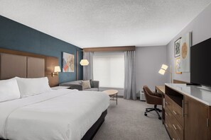 Una habitación de hotel con una cama grande, un escritorio, una silla y un televisor.