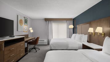 Een hotelkamer met een bed, een bureau met stoel, een televisie en een lamp.