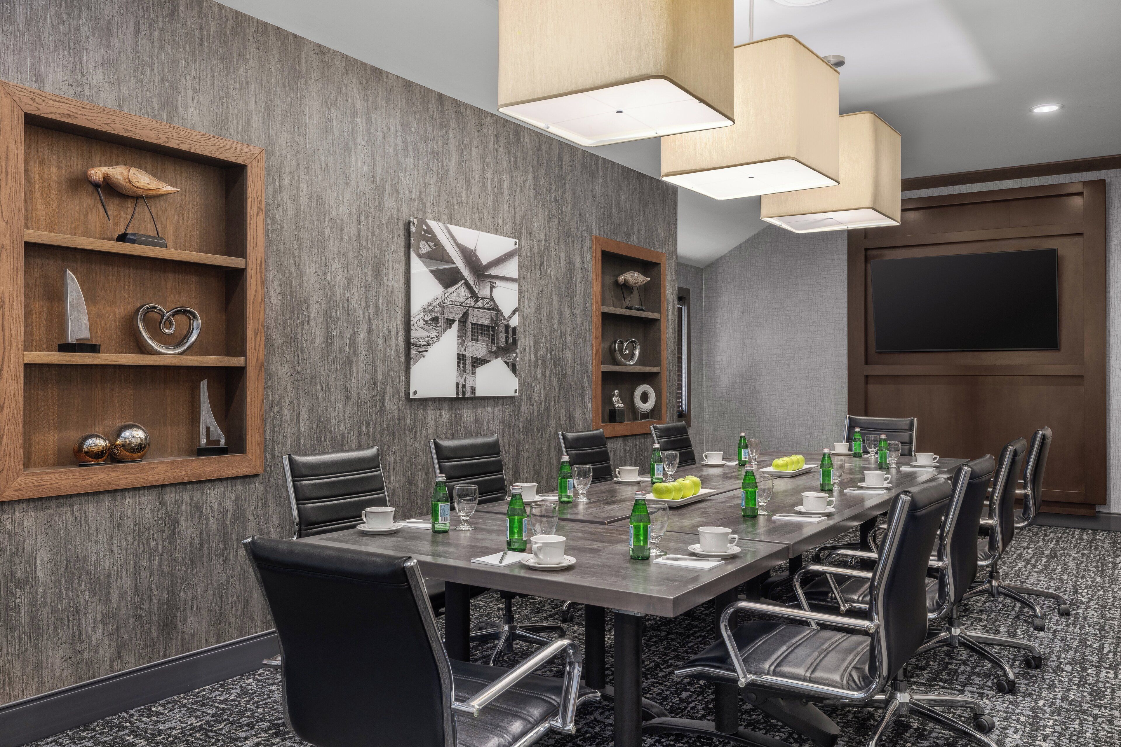 Un salón de conferencias con una mesa larga, sillas y estanterías con adornos.