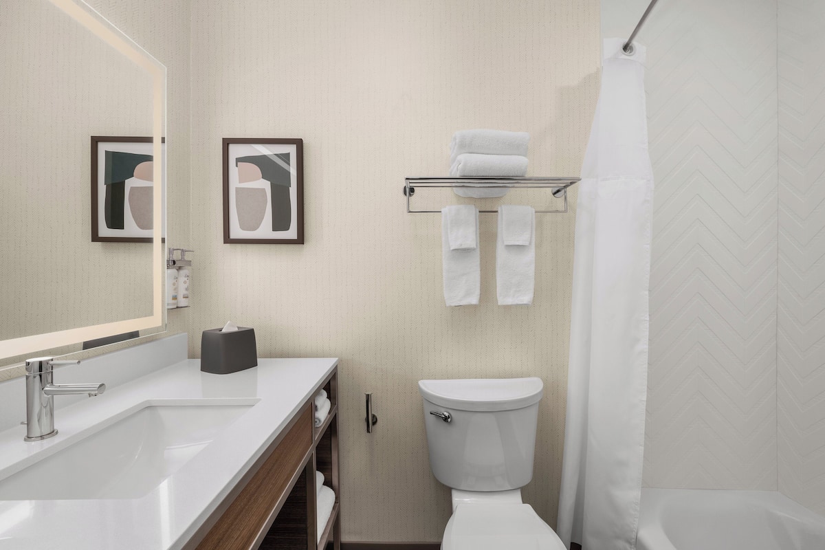 A modern bathroom with a white sink, a toilet, and a shower curtain.