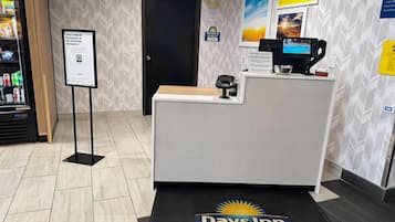 Ein Empfangstresen mit einem digitalen Kiosk, einer Anzeige für die Sofort-Check-in-Möglichkeit und einer Fußmatte mit dem Namen des Hotels.