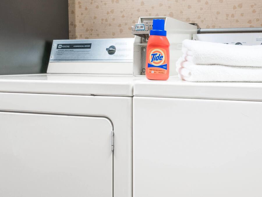 Een voorlader wasmachine met Tide wasmiddel en een opgevouwen witte handdoek erboven.