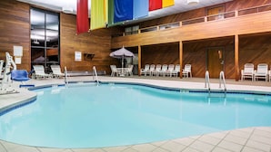 An indoor swimming pool with a wooden interior, multiple lounge chairs, and colorful flags. - Days Inn & Suites by Wyndham Wausau (Wausau)