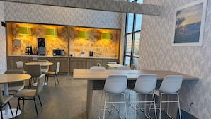 A modern kitchen with two bar areas, bar stools, and a dining table with chairs. - Days Inn & Suites by Wyndham Wausau (Wausau)