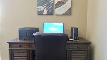 Un escritorio de madera con una computadora de escritorio Dell, una impresora y una silla.