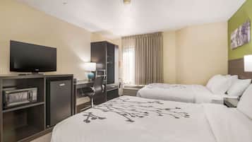 Een hotelkamer met twee bedden, een televisie, een bureau met een computer, een magnetron en een kleine koelkast.