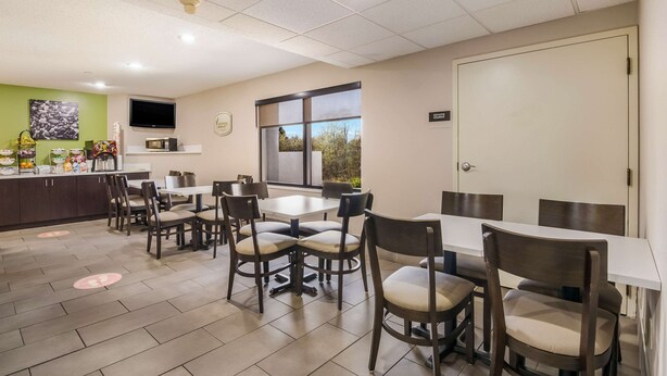 A dining area with tables and chairs, a kitchen counter, a television, and a window with a view. - Sleep Inn Wytheville I-77 and I-81 (Wytheville)