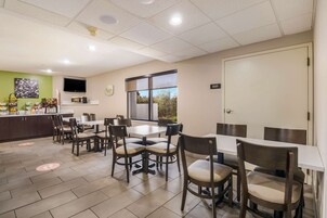 Un comedor con mesas y sillas, una encimera de cocina, un televisor y una ventana con vistas.