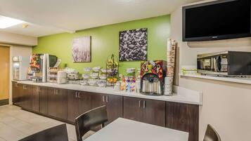 A hotel kitchen with a long counter, various food items, a coffee machine, and a microwave.