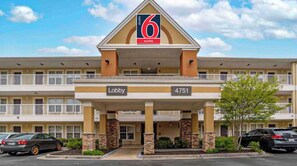 A 6 suites hotel with a lobby entrance, numbered 4751, and a parking area with cars.