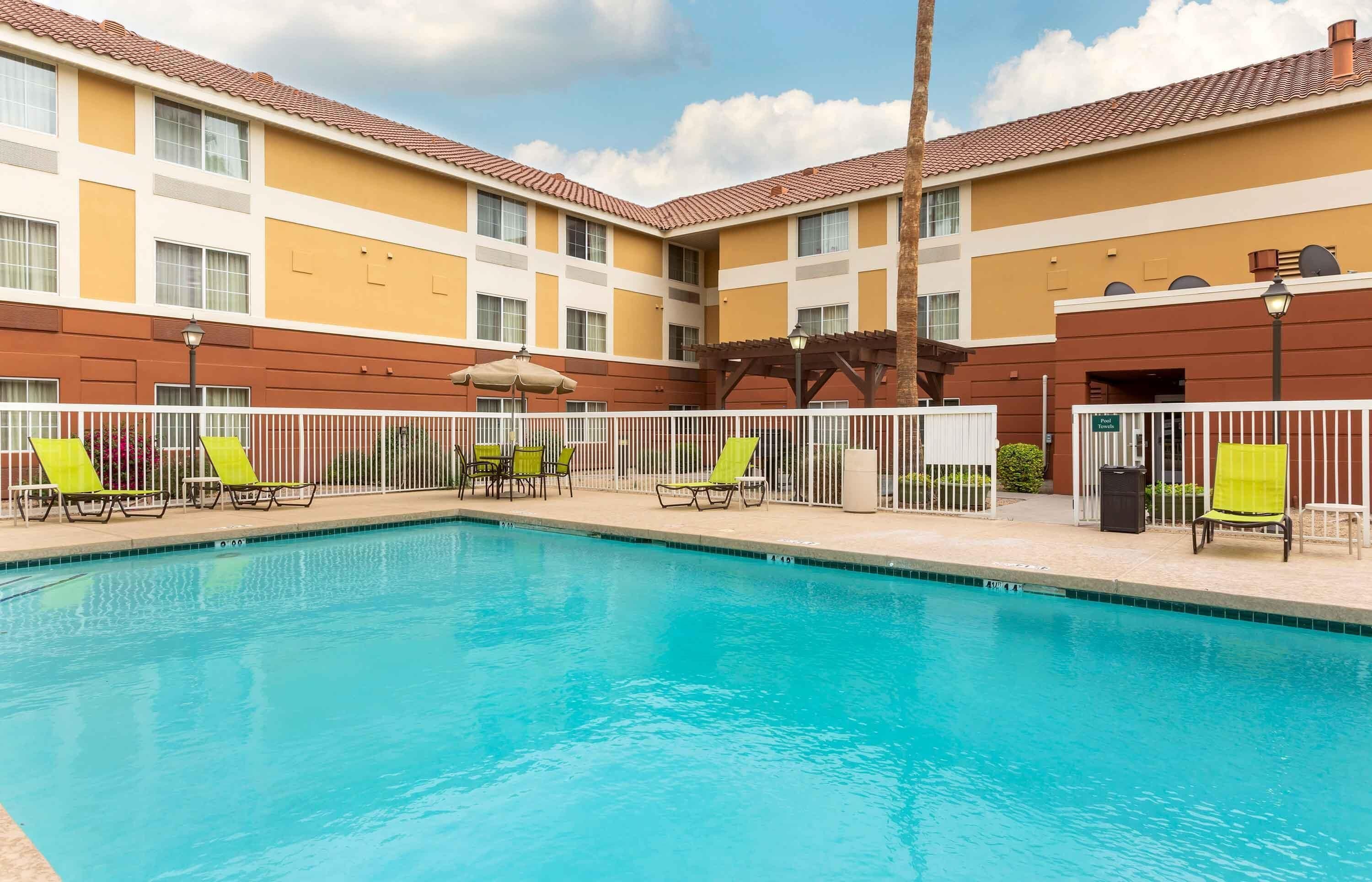A swimming pool with lounge chairs and a building with a tiled roof.