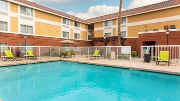 A swimming pool with lounge chairs and a building with a tiled roof.
