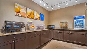A modern kitchen with a coffee machine, a microwave, and a refrigerated display.