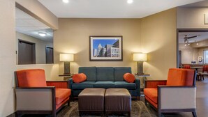 A hotel room with a sofa, two armchairs, a coffee table, a rug, and a framed picture on the wall.