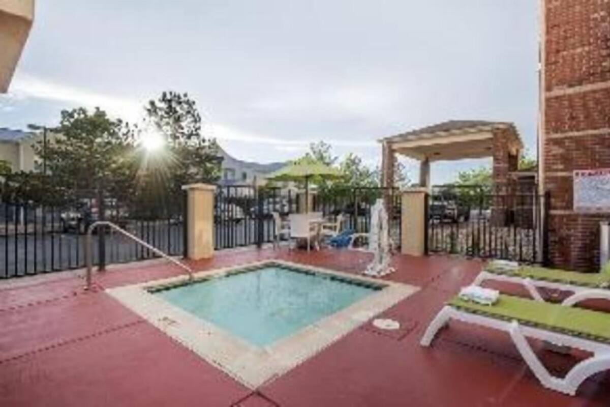 A swimming pool with lounge chairs, a pergola, and a brick wall.