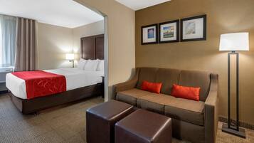 A hotel room with a bed, a sofa, a coffee table, and a lamp.