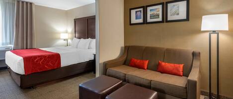 A hotel room with a bed, a sofa, a coffee table, and a lamp.
