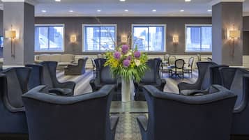 A conference room with a glass table, dark blue chairs, and a floral centerpiece.