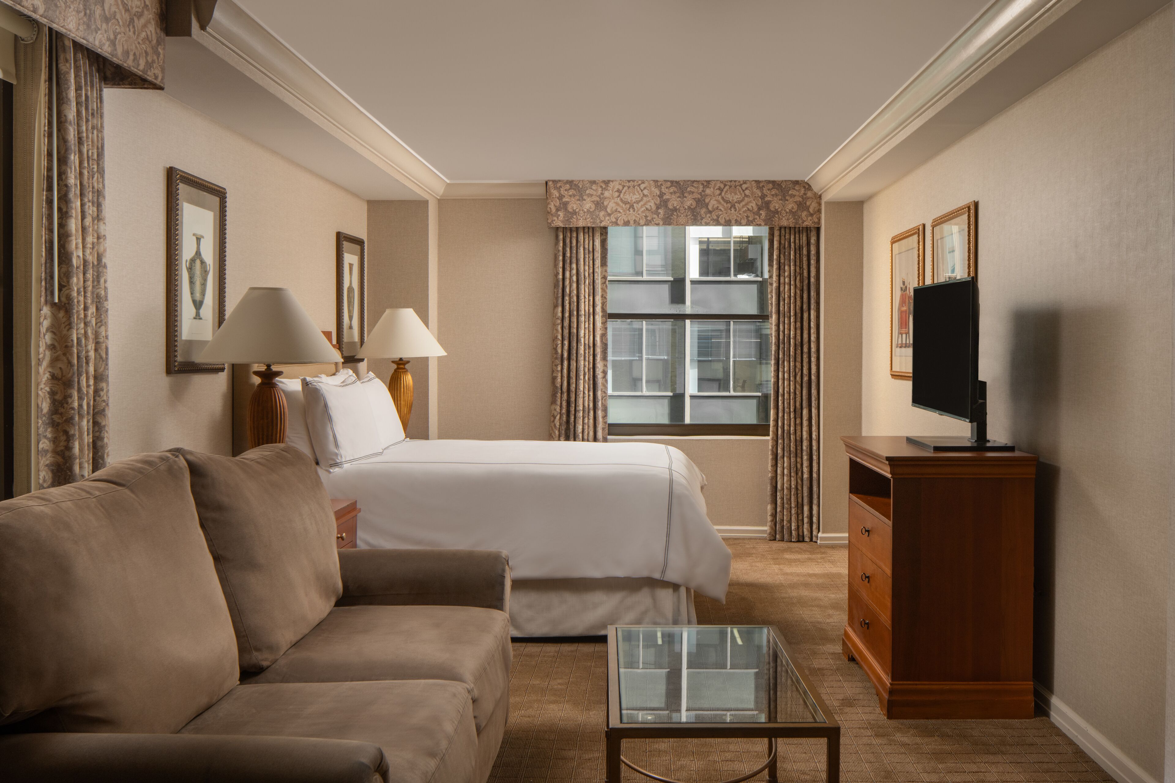 Ein Hotelzimmer mit Bett, Sofa, Fernseher und einem kleinen Tisch.