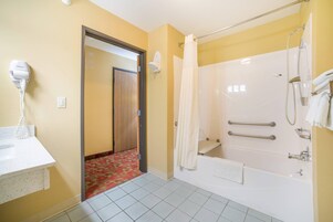 A bathroom with a shower, a bathtub, a hairdryer, and a towel rack.