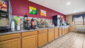 A breakfast bar with a fruit juice dispenser, coffee maker, and various breakfast items.