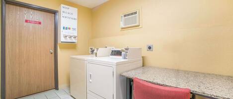 A laundry room with a washing machine, dryer, and a sign listing soap, bleach, and softeners.