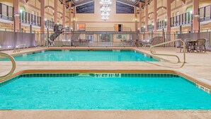 Una piscina interior con agua cristalina, rodeada por una solana con baldosas y una barandilla.