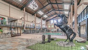 Un atrium interior con una fuente central, suelo de piedra y una valla de metal.