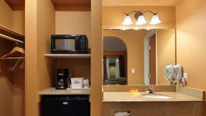 Un baño con microondas, cafetera y lavamanos con toallero.