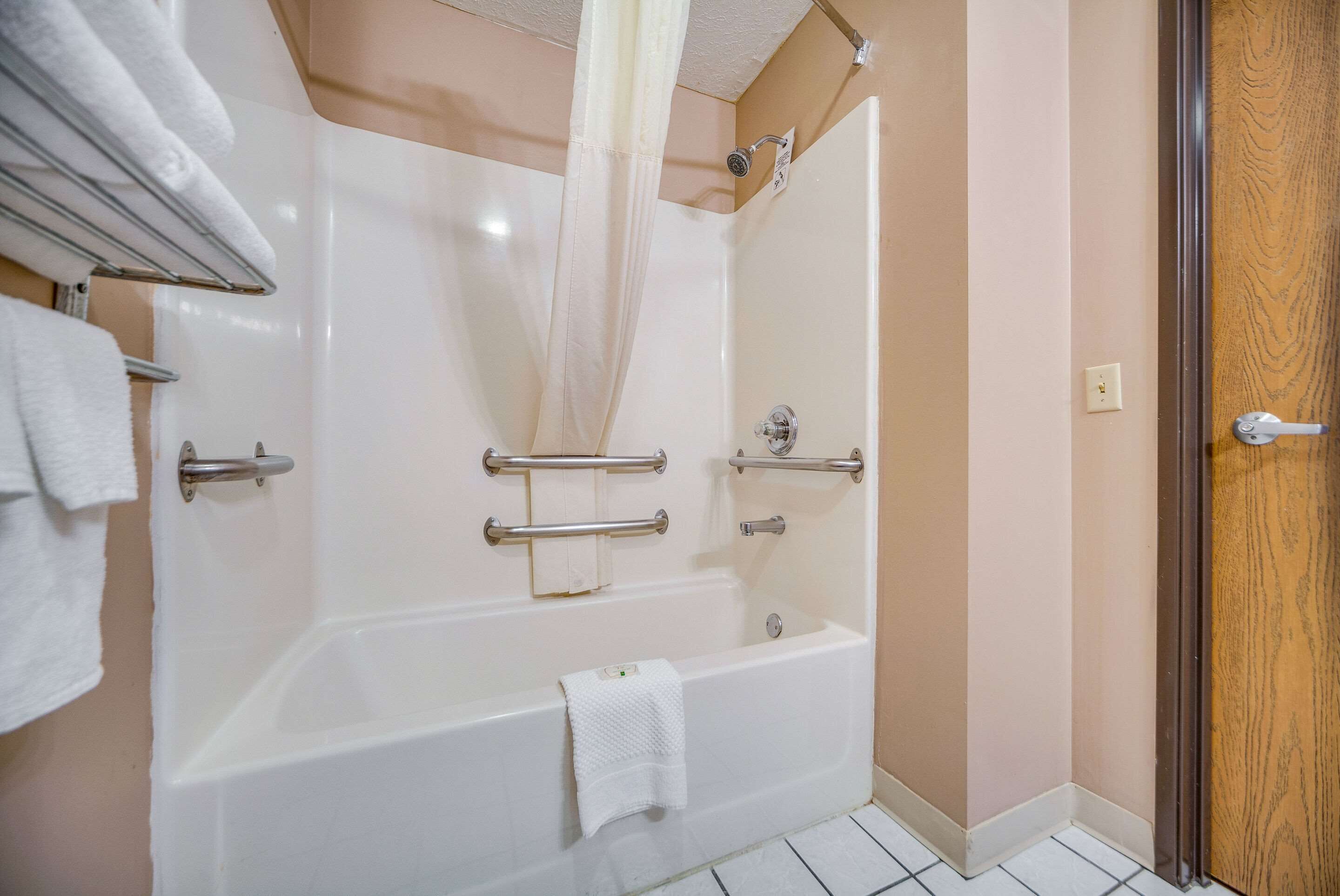 Un baño con bañera, cortina de ducha y puerta de madera.