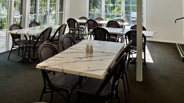 A spacious indoor dining area with high ceilings, large windows, and modern chandeliers.