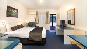 A hotel room with a bed, desk, chair, and television.