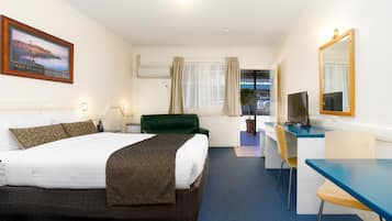Habitación de hotel con una cama grande, un escritorio con silla, un televisor y una ventana con cortinas.