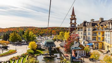 A town square with a central fountain, surrounded by buildings with a clock tower, and a backdrop of autumn-colored trees.