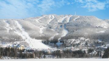 Une montagne enneigée, avec des pistes de ski et une ville située à son pied.