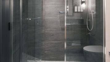 A modern bathroom with a glass shower enclosure, a toilet, and a sink.