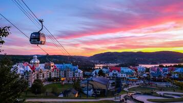 A cable car moving over a town with colorful buildings and a lake in the background.
